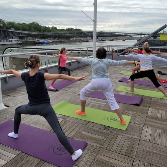 Groupe de femmes réalisant une posture de yoga sur le pont d'un bateau à Paris